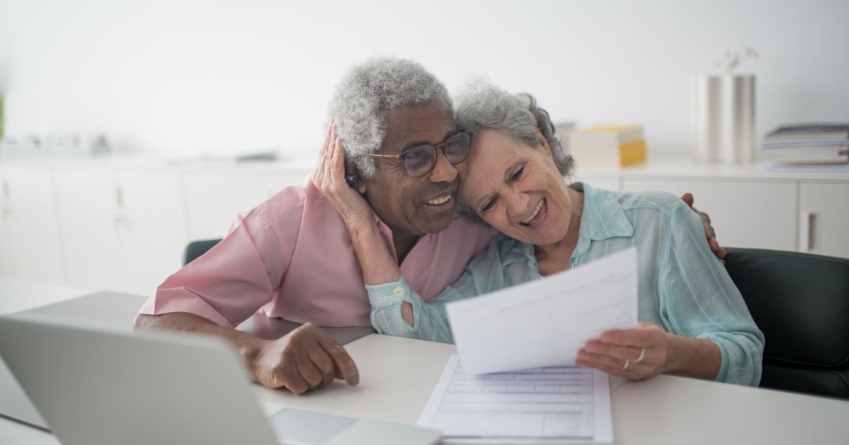 Older couple smiling while reading a document together at a table
