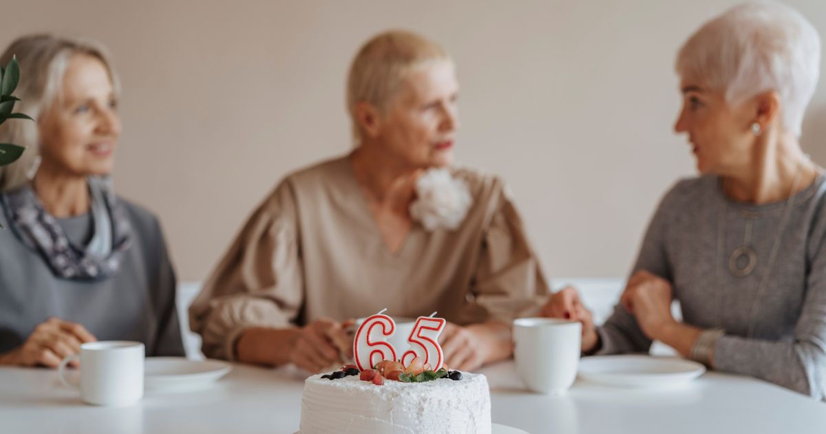 Three senior women celebrating a 65th birthday with cake and coffee