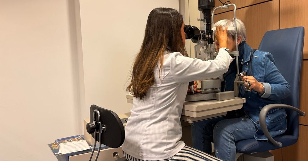 Optometrist examining an older patient at a slit lamp in a clinic exam room