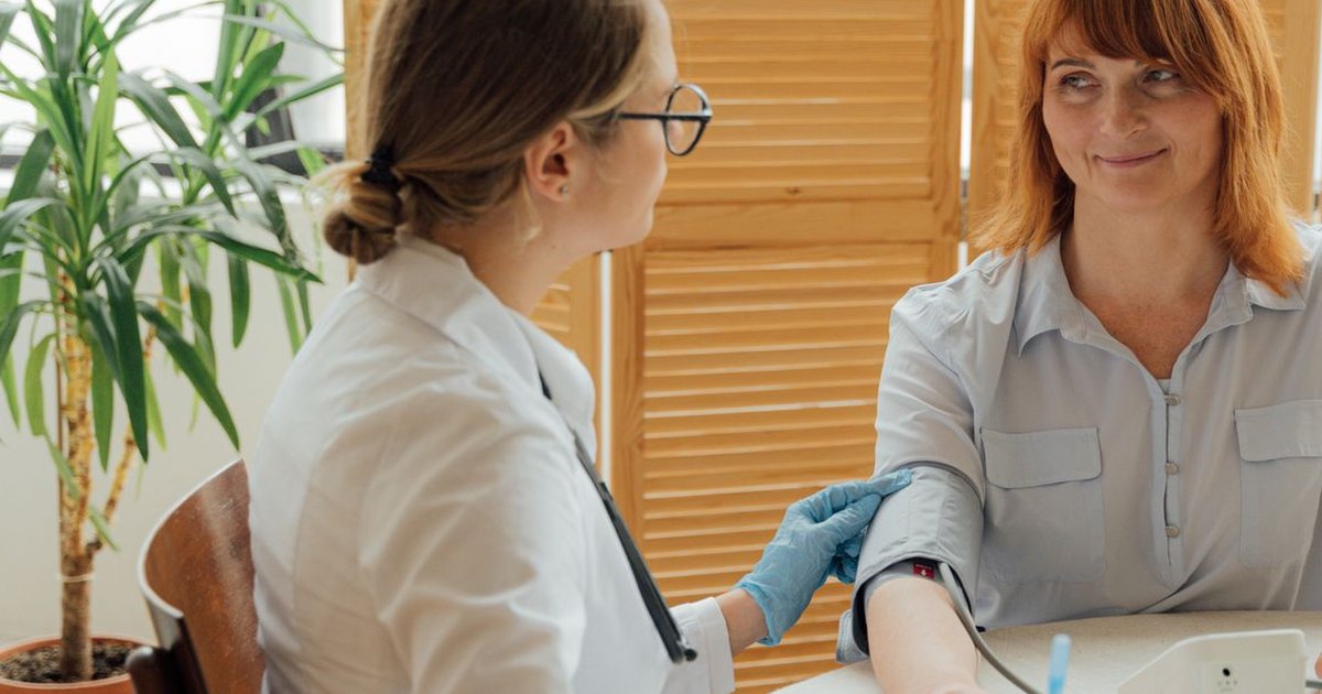 Health care provider taking a middle-aged woman's blood pressure during an office visit
