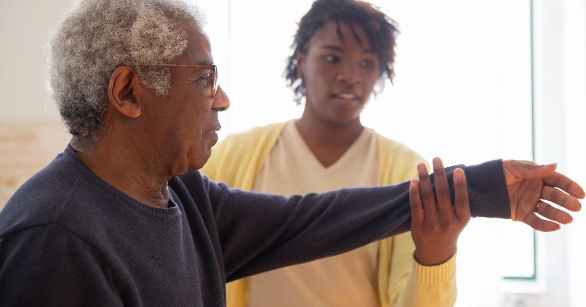 Physical therapist helping an older adult with an arm mobility exercise