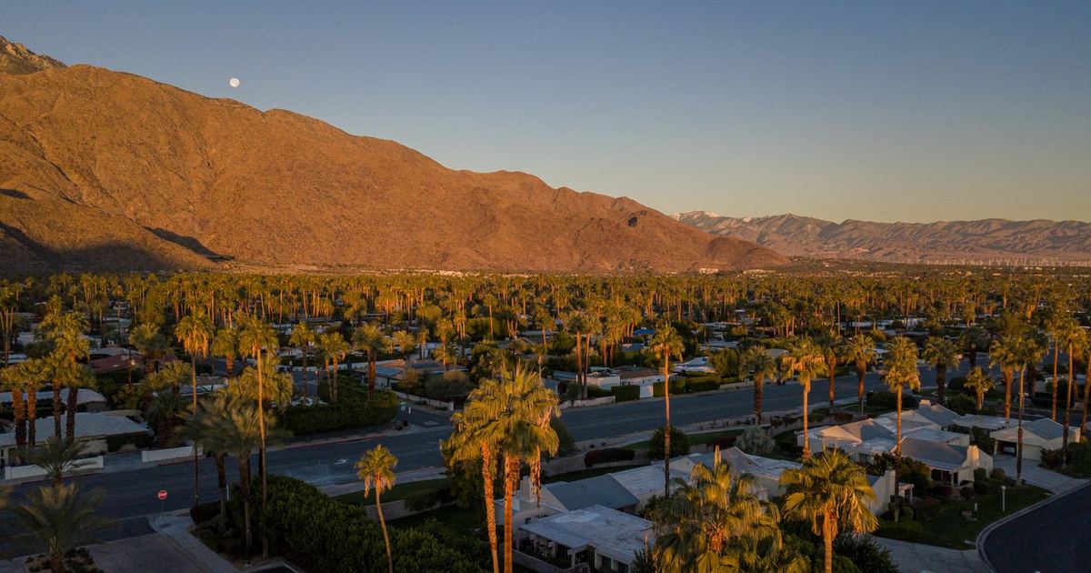Aerial view of a Palm Springs neighborhood at sunset, with palm trees and the San Jacinto Mountains behind