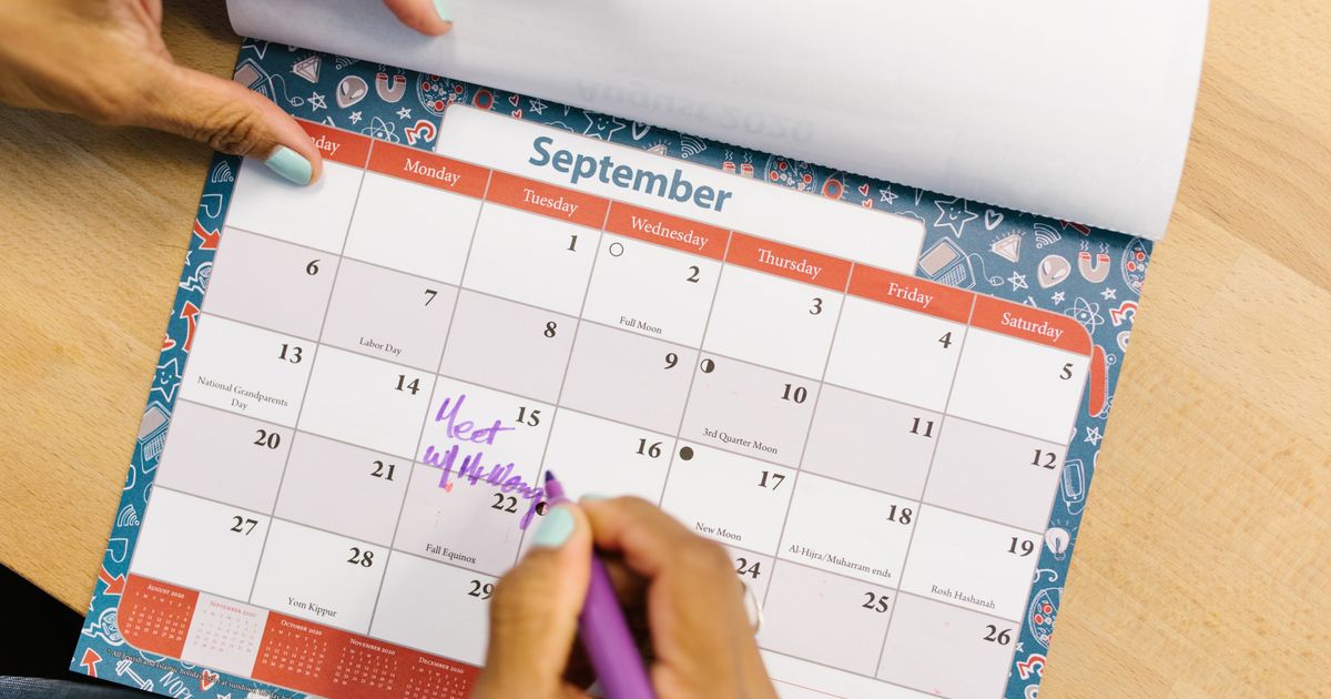 Person marking enrollment dates on a calendar