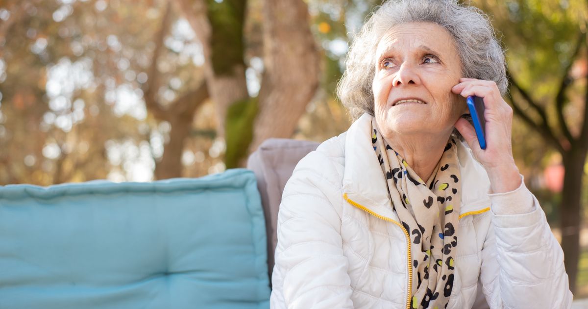 Older woman listening carefully during a phone call while sitting outdoors
