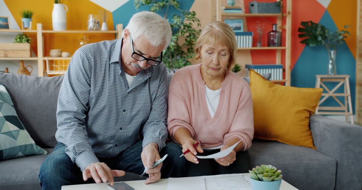 Senior couple at home reviewing a bill together with a phone calculator